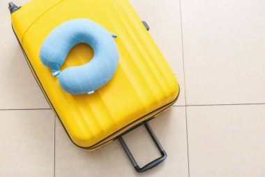 Seyahat yastığı ve bavul odada yerde.