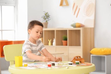 Evdeki resimleri boyayan sevimli küçük çocuk.