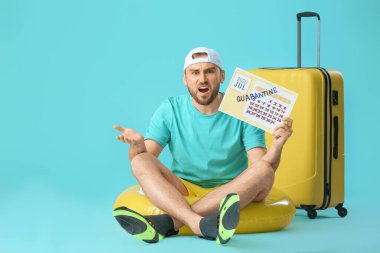 Angry man holding calendar with written word QUARANTINE against color background. Vacation concept clipart