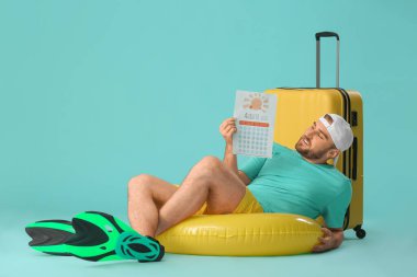 Takvim ve bavulu renkli genç bir adam. Tatil kavramı