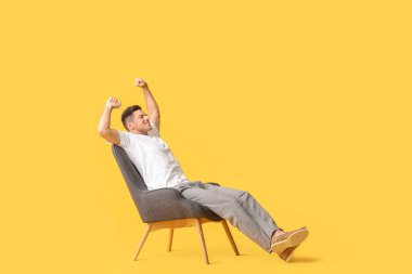 Genç adam renk arka planına karşı koltukta dinleniyor