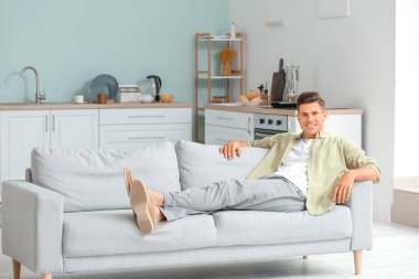 Evdeki kanepede dinlenen genç adam.