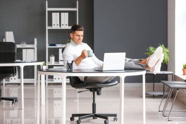 Genç adam işyerinde kahve içiyor.