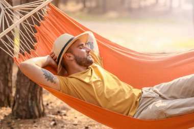 Genç adam dışarıda hamakta dinleniyor.