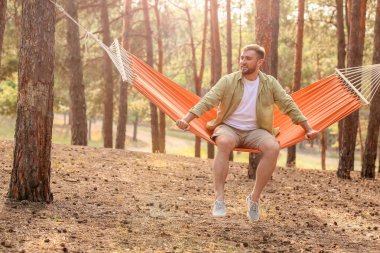Genç adam dışarıda hamakta dinleniyor.