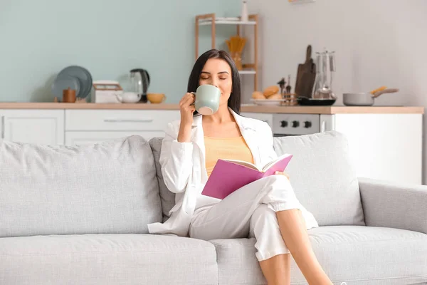Young Woman Reading Book Drinking Coffee While Relaxing Sofa Home — Stock Photo, Image