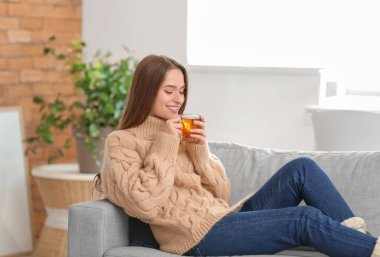 Güzel genç bayan evde çay içiyor.