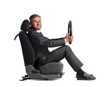 Direksiyon başında beyaz arka planda oturan genç bir işadamı.