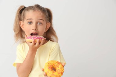 Hafif arka planda donutları olan komik küçük bir kız.
