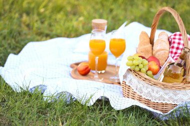 Parkta romantik piknik için içinde lezzetli yemekler ve içecekler olan sepet.