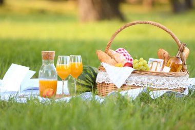 Parkta romantik piknik için içinde lezzetli yemekler ve içecekler olan sepet.