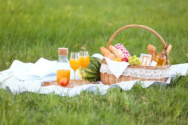 Parkta romantik piknik için içinde lezzetli yemekler ve içecekler olan sepet.