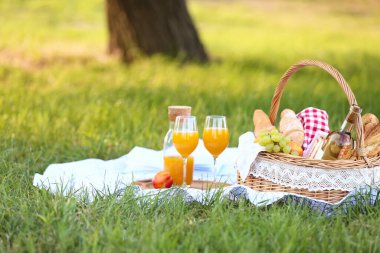 Parkta romantik piknik için içinde lezzetli yemekler ve içecekler olan sepet.