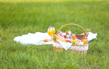 Parkta romantik piknik için içinde lezzetli yemekler ve içecekler olan sepet.