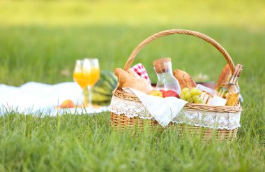 Parkta romantik piknik için içinde lezzetli yemekler ve içecekler olan sepet.
