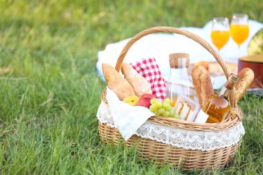 Parkta romantik piknik için içinde lezzetli yemekler ve içecekler olan sepet.