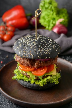 Esmer arka planda siyah çörekli lezzetli bir hamburger.