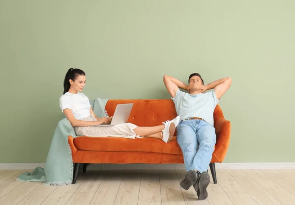 Pareja Joven Relajándose Sofá Cerca Pared Color —  Fotos de Stock