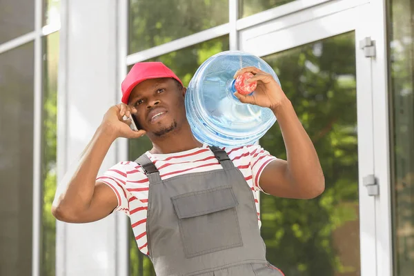 African American Delivery Man Bottle Water Talking Mobile Phone Outdoors — Stock Photo, Image