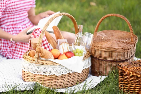 Basket with tasty food and drink for romantic picnic in park