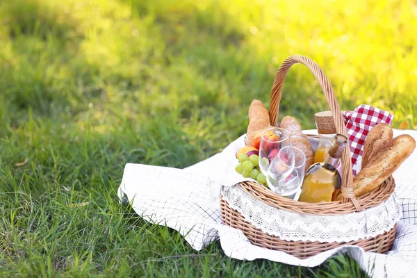 Basket with tasty food and drink for romantic picnic in park