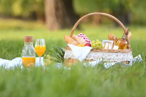 Parkta romantik piknik için içinde lezzetli yemekler ve içecekler olan sepet.