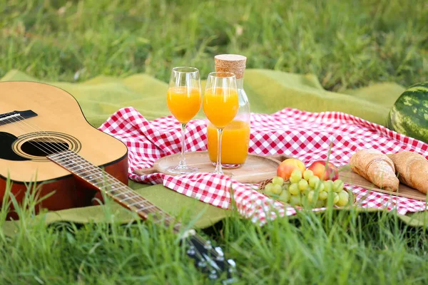 Parkta romantik piknik için lezzetli yemekler, içecekler ve gitarlar.