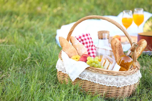 Parkta romantik piknik için içinde lezzetli yemekler ve içecekler olan sepet.