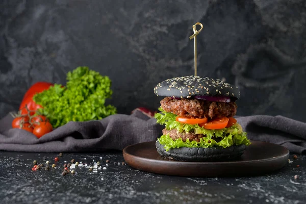 Tasty burger with black bun on dark background