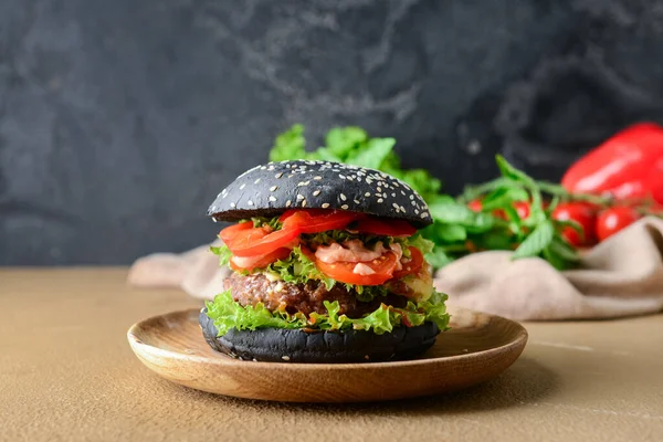 Tasty burger with black bun on table