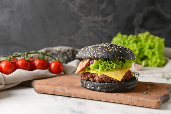 Tasty burger with black bun on table