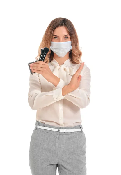 Female makeup artist with medical mask showing stop gesture on white background. Coronavirus epidemic