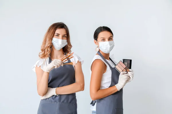 Female makeup artists wearing medical masks on light background. Coronavirus epidemic