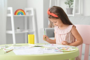 Evde resim boyayan sevimli küçük bir kız.