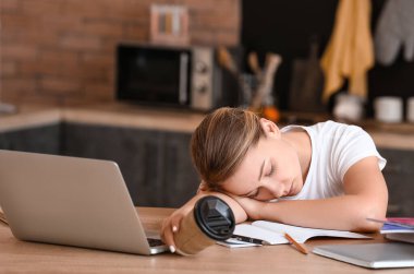 Yorgun öğrenci masada uyuyor.