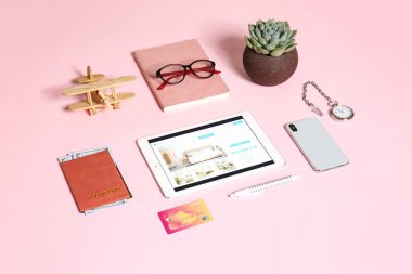 Modern tablet bilgisayar ve seyahat aksesuarları renk arka planında. Çevrimiçi rezervasyon kavramı