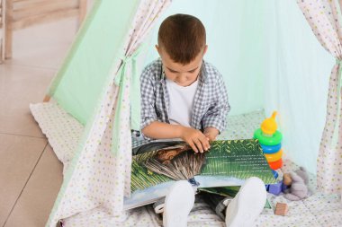 Evde kitap okuyan şirin bir çocuk.