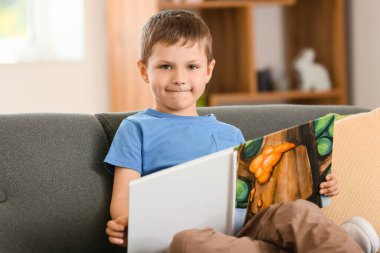 Evde kitap okuyan şirin bir çocuk.