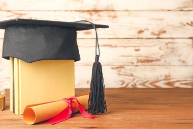 Mezuniyet şapkası, kitaplar ve diploma masada.