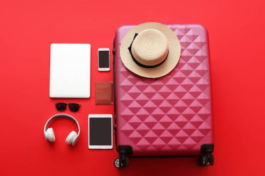 Arkaplanda aksesuar ve cihazlarla dolu bir bavul. Seyahat kavramı