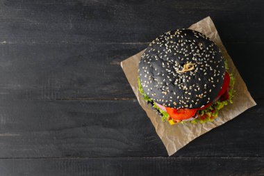 Esmer arka planda siyah çörekli lezzetli bir hamburger.