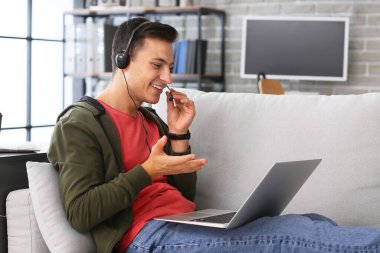 Ofiste çalışan kulaklıklı ve laptoplu bir adam.