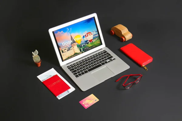 Modern laptop and travel accessories on dark background. Concept of online booking