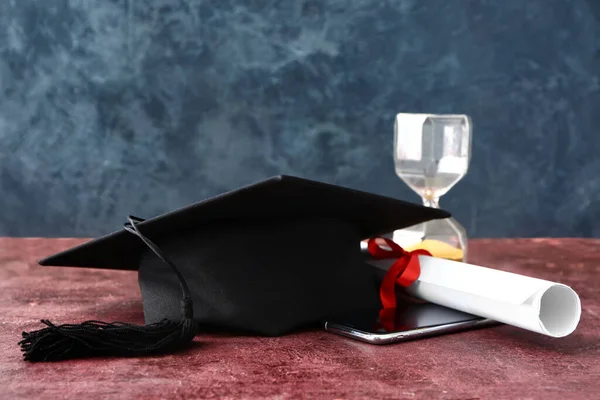 毕业帽 沙漏和毕业证书放在桌上 — 图库照片