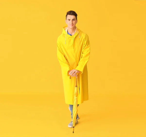 ハンサムな若いです男でレインコートと傘で色の背景 — ストック写真