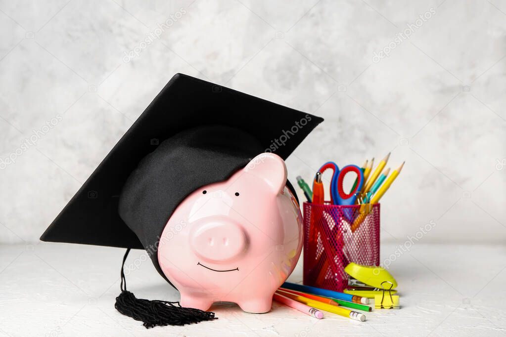 Piggy bank, graduation hat and stationery on table. Tuition fees concept