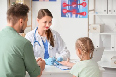 Klinikteki küçük kızın kan şekerini ölçen doktor.