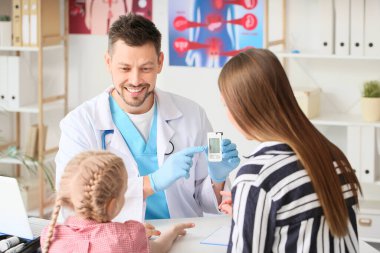 Klinikteki küçük kızın kan şekerini ölçen doktor.