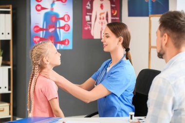 Doktor, klinikte tiroid bezi sorunu olan küçük bir kızı muayene ediyor.
