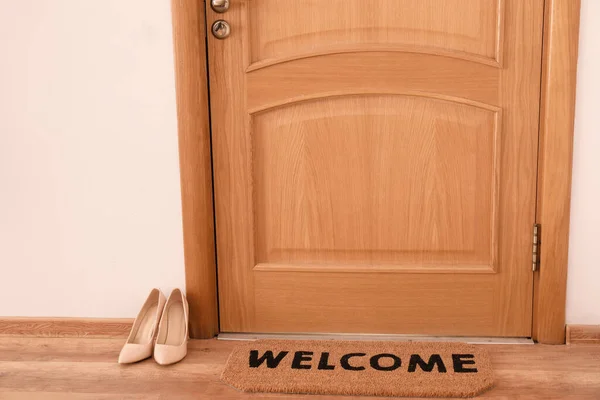 Door mat and female shoes on floor in hallway